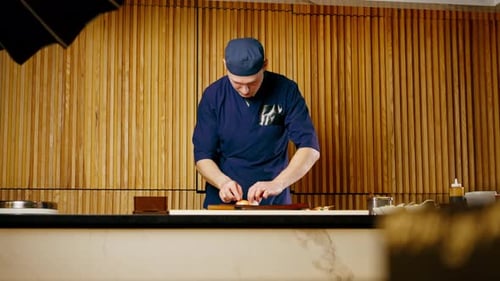 in Japanese Restaurant the Chef Lays Out Pieces of Raw Fish on a Long Red Plate