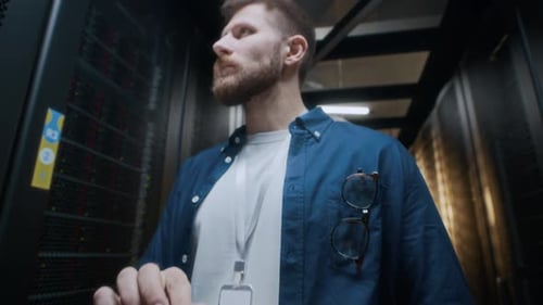 Young Concentrated IT Engineer Monitoring Hardware Work in Data Center