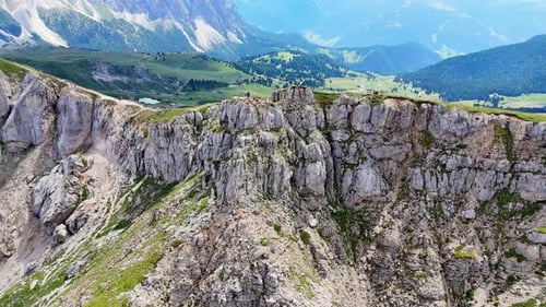 Tourists hiking on mountain path approaching cliff