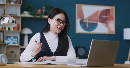 Woman Attends Video Conference and Takes Notes at Home