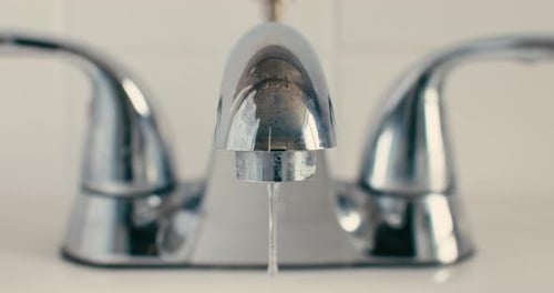 Close-Up of Chrome Bathroom Faucet with Water Droplet Reflection