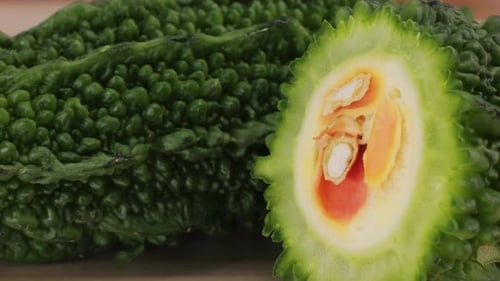 Une gourde amère, un légume souvent utilisé comme ingrédient en cuisine, est posée sur une table en bois.