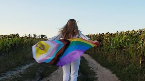 Woman Runs with Pride Flag Through Sunflower Field