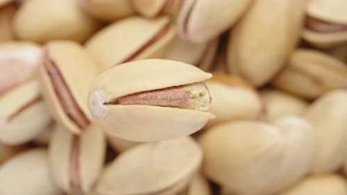 One salted pistachio rotates on a background of pistachios. macro.