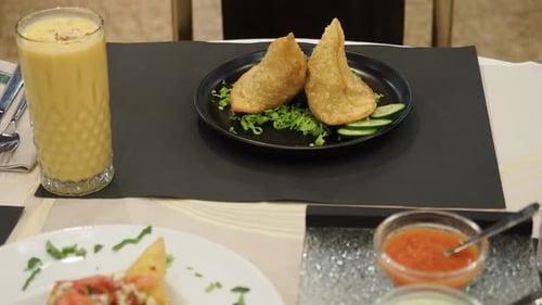 Zwei köstliche Samosas, die auf einem Salatbett auf einem schwarzen Teller ruhen