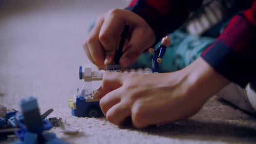 Un niño construye un trolebús con ladrillos sentado en el suelo