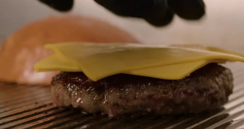 Chef Places Cheese on Hamburger Patty on Grill