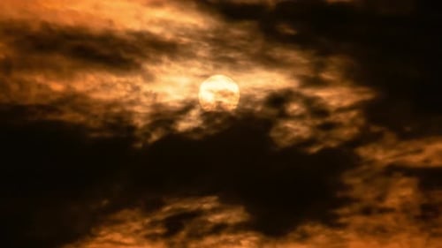Golden Sun Peeks Through Dramatic Clouds at Sunset