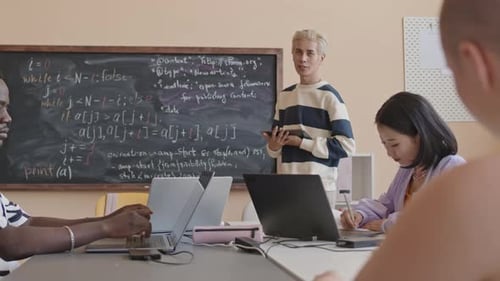 Junger asiatischer Lehrer spricht im Programmierunterricht mit Studenten