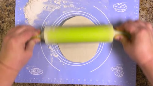 Rolling out round pieces of raw dough with a rolling pin to make patties. Top view.