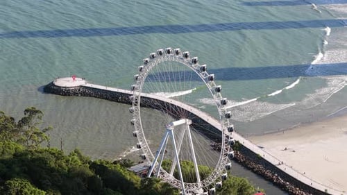 Aerial view of large ferris wheel next to pier walkway on Balneário Camboriú beach. in Brazil.