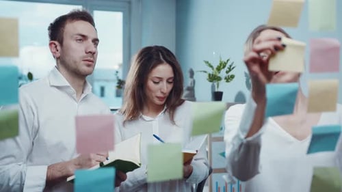 In Office Team of Young Managers and Workers Look on Sticker on Glass During Business Meeting and
