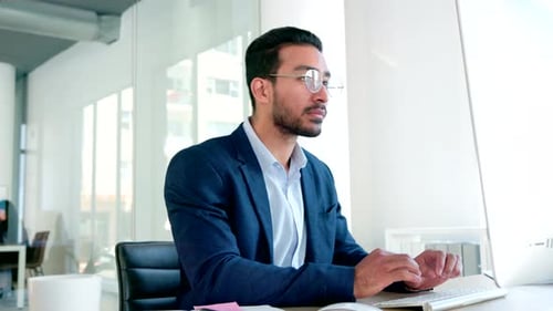 Male software developer coding software on a desktop computer in an office