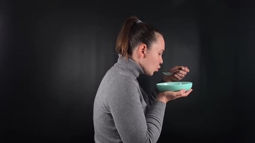 Woman Eating From Bowl in a Kitchen