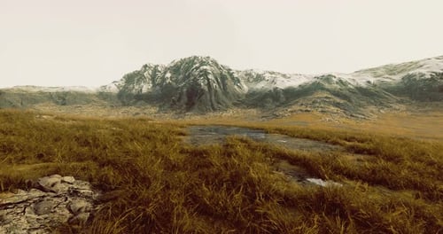 Majestic Mountain Landscape with Golden Grass and Snow Capped Peaks at Dawn