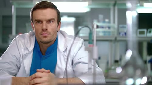 Pensive man in laboratory coat with glassware