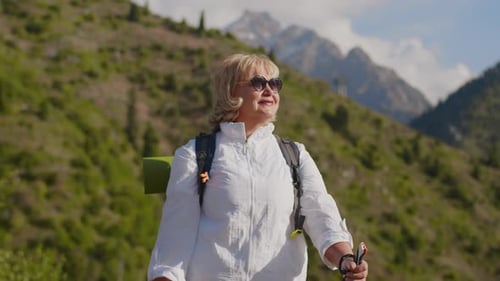 Portrait of a Senior Woman with a Backpack Looking Around the Perfect Mountain Landscape As a