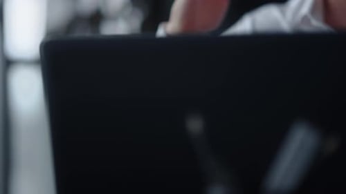 Man Answering Phone Next to Laptop During the Day