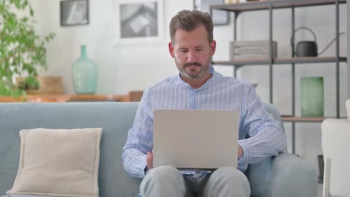 Man Working on Laptop at Home During Daytime