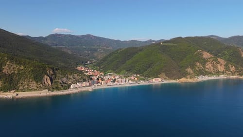 Aerial view of a charming Italian coastal town on a bright, sunny day with mountains