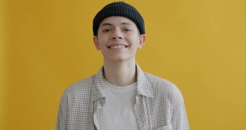 Slow Motion Portrait of Overjoyed Teenage Boy Laughing Having Fun Against Yellow Color Background