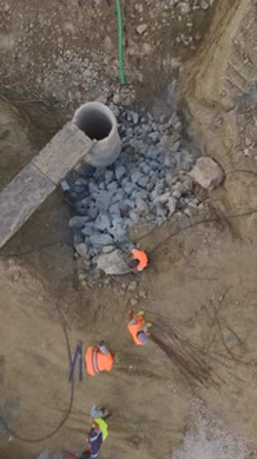 Workers Laying Pipe in Ground Trench
