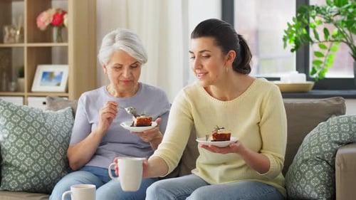 Two women enjoying cake together on a couch