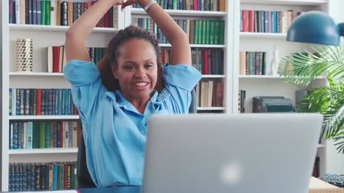 Smiling Woman Stretching at Desk with Laptop