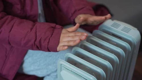 Woman Warming Her Hands Near the Heater