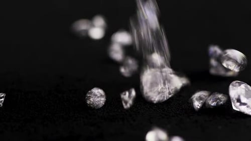 Diamonds falling onto black surface close up shot