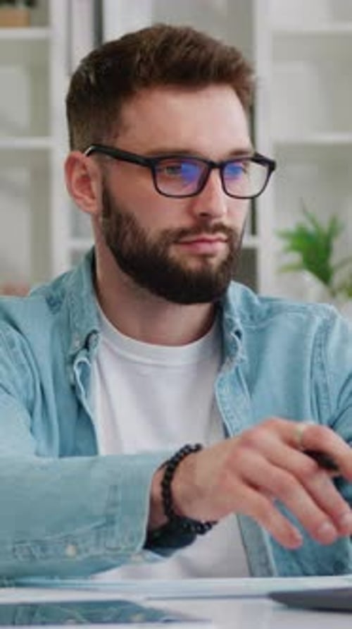 Focused Business Man Entrepreneur Typing on Laptop Sitting at Desk in Home Office Making Notes
