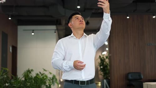 Man Troubleshooting Cell Service on Smartphone in Office