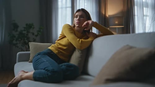 Apathetic Woman Feeling Sleepy on Sofa in Living Room Lady Looking Distance