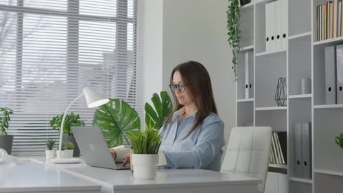 A Dedicated and Focused Professional Woman is Seen Working Efficiently in a Modern Office Space