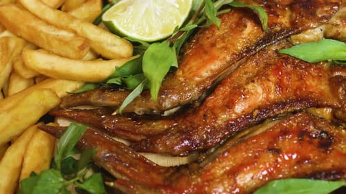 Grilled chicken wings alongside golden french fries, garnished with fresh