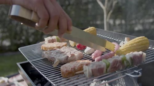 Nahaufnahme von männlicher Hand beim Umdrehen von Würstchen auf dem Barbecue-Grill