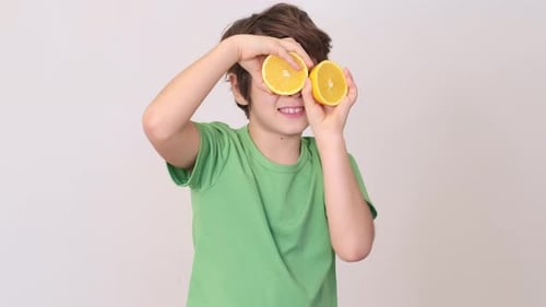 Young Boy Posing with Sliced Oranges Over Eyes