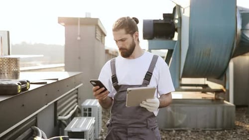 Male Master Holding Tablet and Using Smartphone on Roof