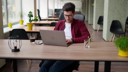 Young Adult Works on Laptop in Office