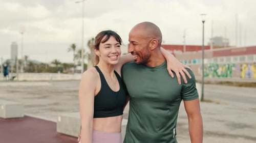 Close-up of dialogue between a man and a woman by the sea, a sporty couple walking and hugging