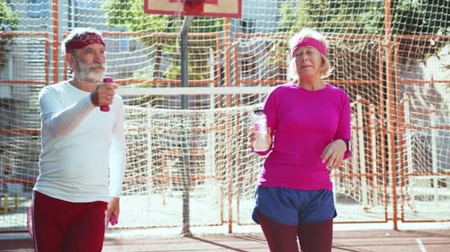 Elderly Fitness Enthusiasts Actively Engaging in Exercising on the Sports Court Together