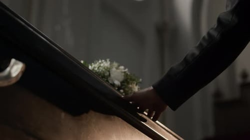 Hand on Coffin with Flowers in Soft Light