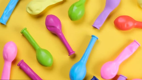 Rotating Multicolored Balloons on a Yellow Background Top View the Concept of Celebrating a Birthday