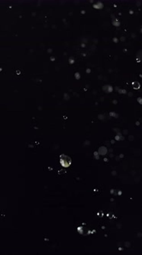 Wassertröpfchen bewegen sich im Dunkeln in Zeitlupe