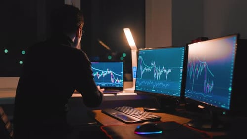 Midnight Trading CloseUp of Young Man Analyzing Charts on Computer Monitor