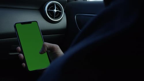 Using smartphone inside the car tapping and swiping holding phone with green screen