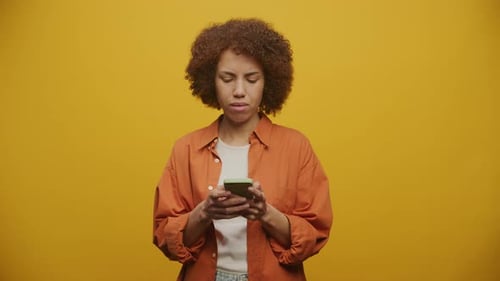 Woman Using Smartphone on Yellow Background