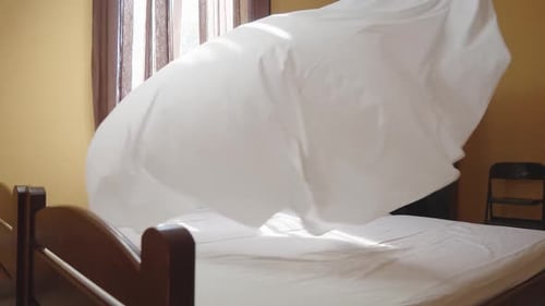 Female Housekeeper Changing Bedding in a Hotel Room