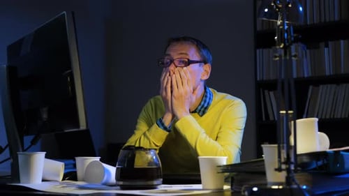 Man Rubbing His Eyes While Working Overtime