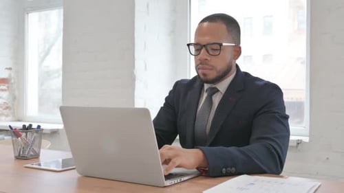 Man in Suit Typing at Desk with Laptop